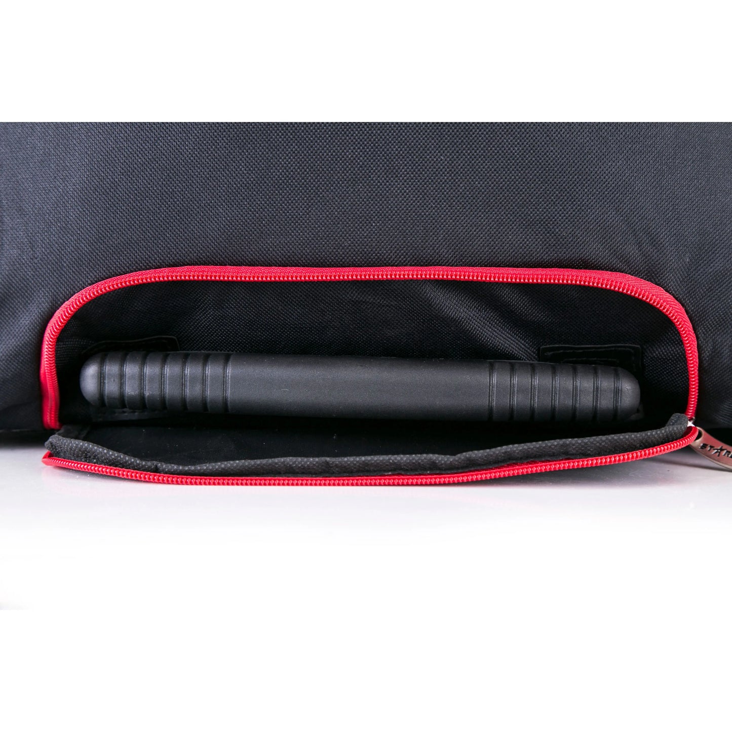Black cylindrical object inside a black bag with red interior lining on a white background