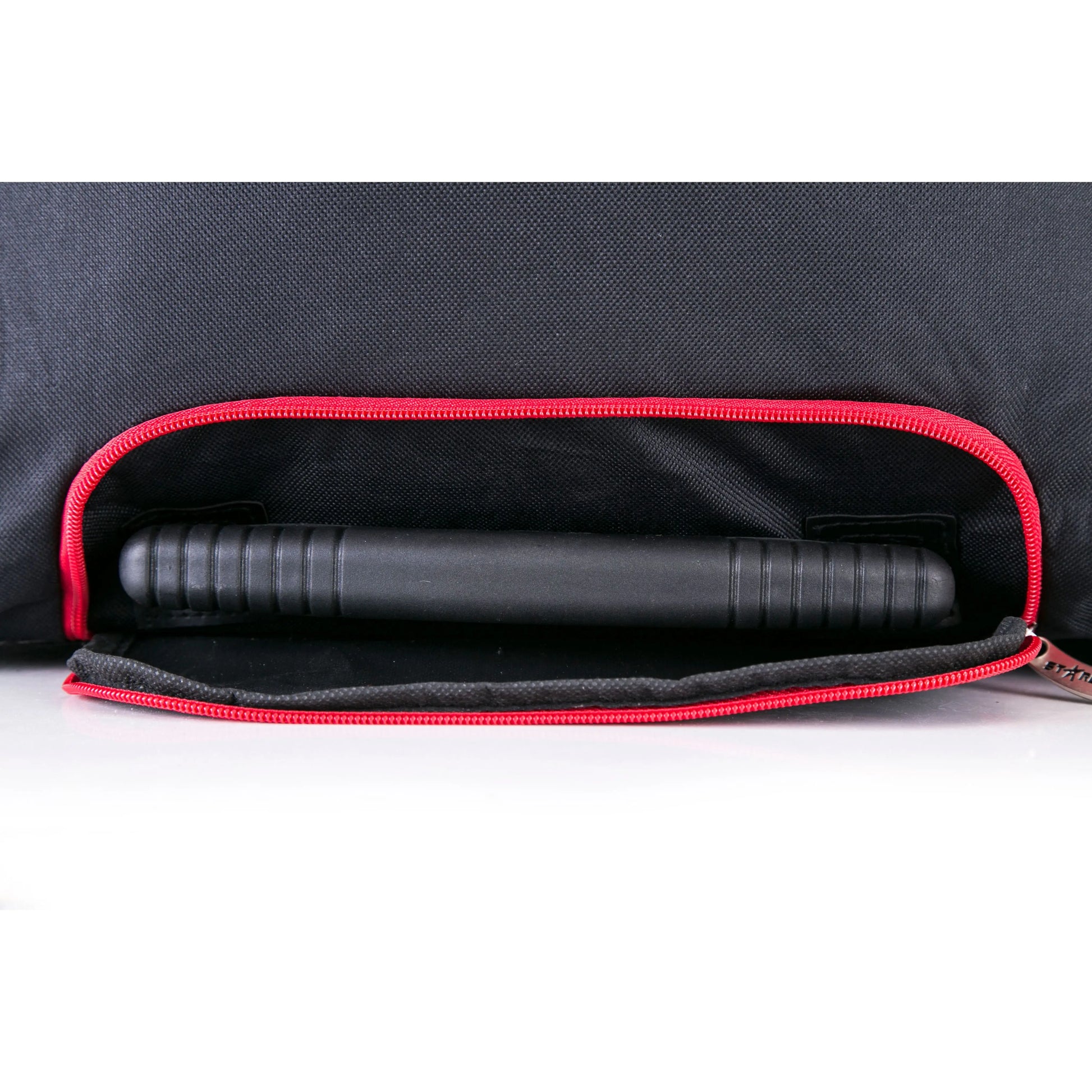 Black cylindrical object inside a black bag with red interior lining on a white background